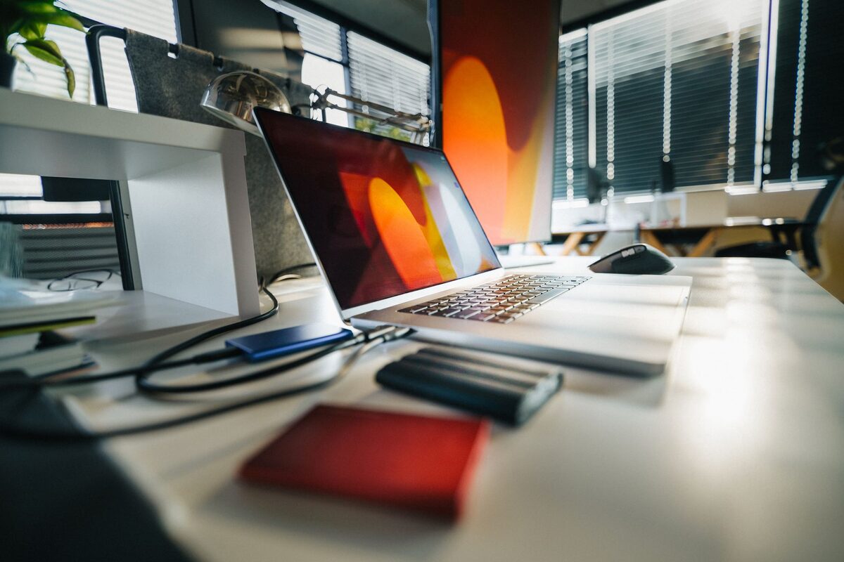 Laptop z kolorowym ekranem na biurku obok dysków zewnętrznych
