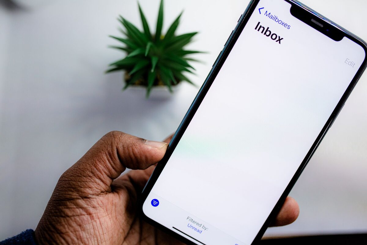 Dłoń trzymająca telefon z ikoną poczty
