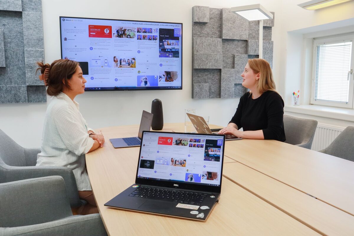 Dłoń przy laptopie z ekranem programu firmowego