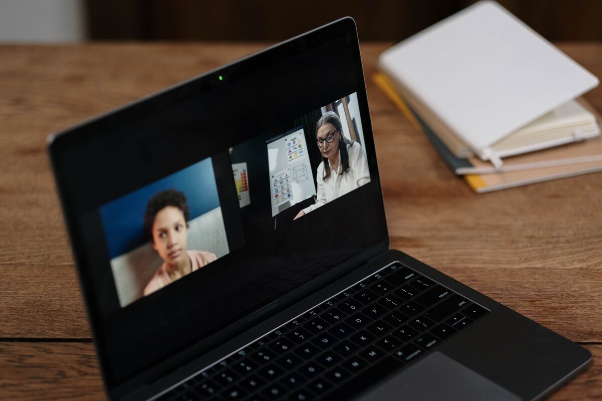 Laptop z ekranem wideokonferencji obok notesu