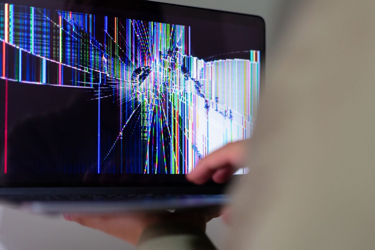 Laptop z pękniętym, uszkodzonym ekranem trzymany w dłoniach