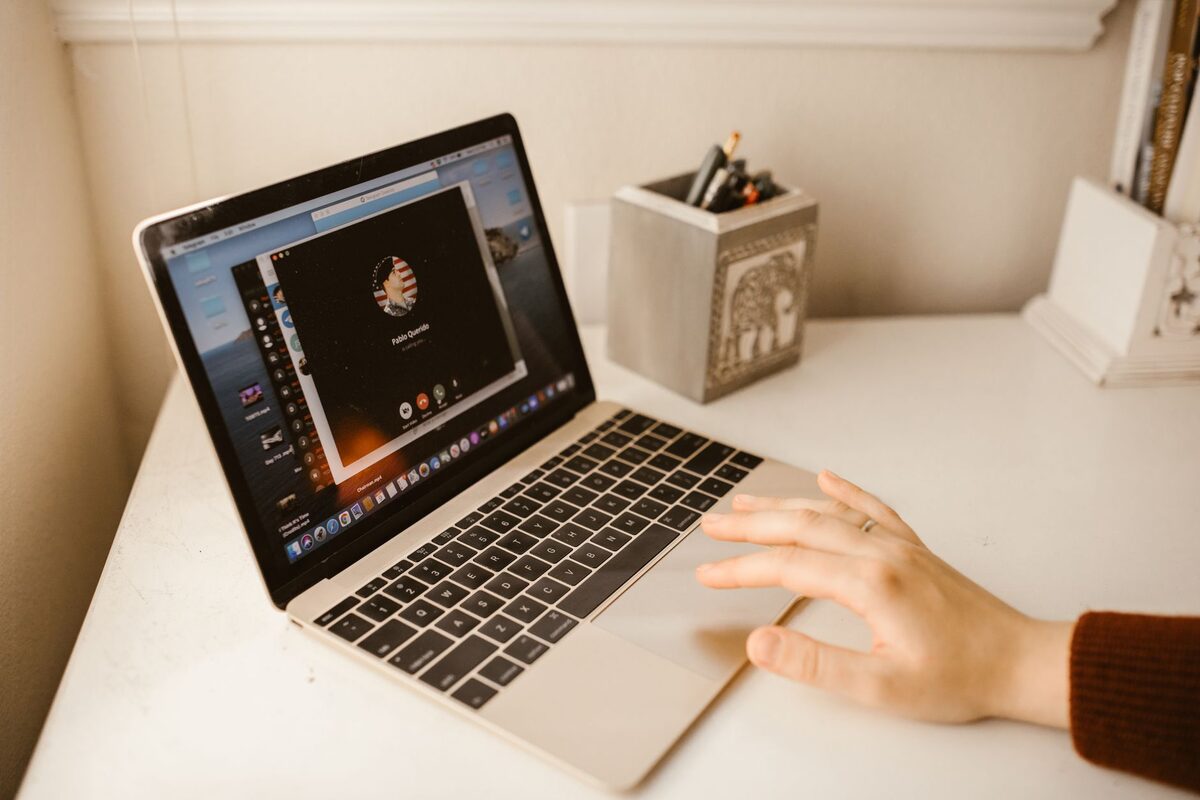 Dłoń przy laptopie z ciemnym ekranem na drewnianym biurku